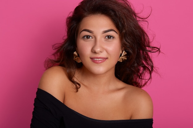 Foto de estudio de joven fascinante con cara bonita y cabello castaño ondulado