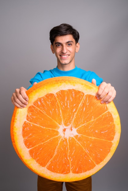 Foto de estudio de joven guapo adolescente persa contra un fondo gris