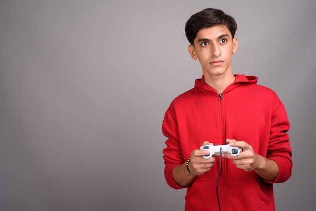 Foto de estudio de joven guapo adolescente persa contra un fondo gris