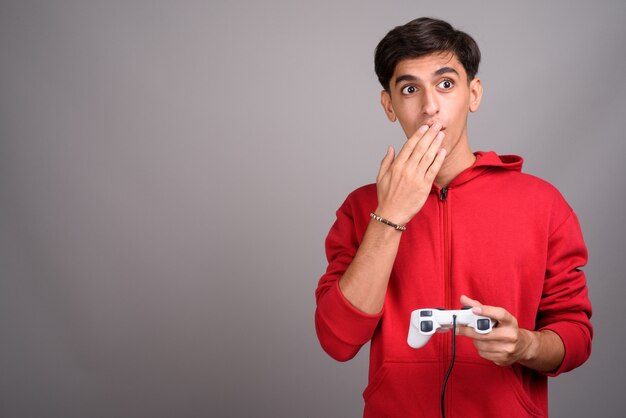 Foto de estudio de joven guapo adolescente persa contra un fondo gris