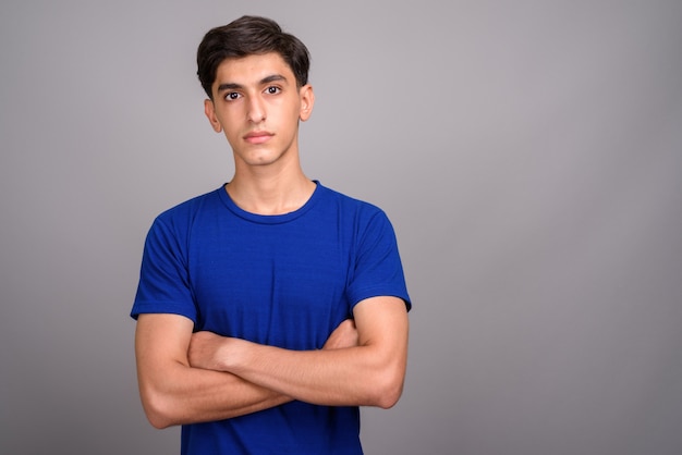 Foto de estudio de joven guapo adolescente persa contra un fondo gris