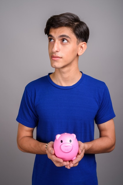 Foto de estudio de joven guapo adolescente persa contra un fondo gris