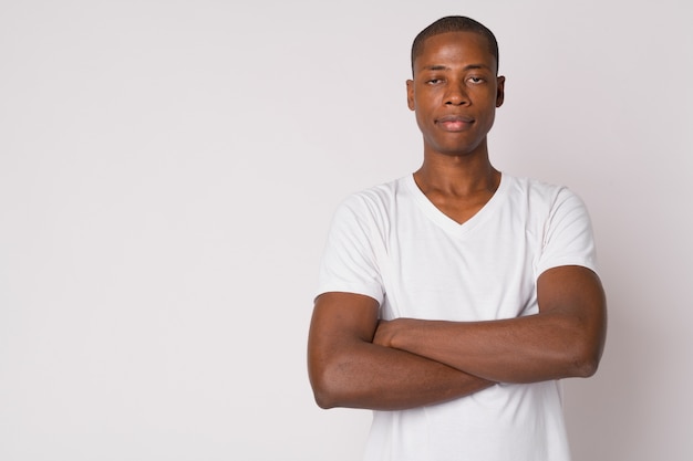 Foto de estudio de joven guapo africano calvo contra el fondo blanco.