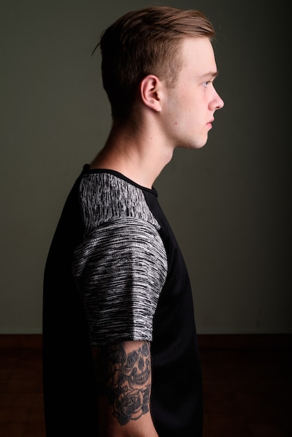 Foto de estudio de joven guapo con cabello rubio contra el fondo de color