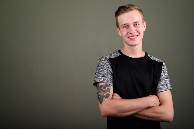 Foto de estudio de joven guapo con cabello rubio contra el fondo de color