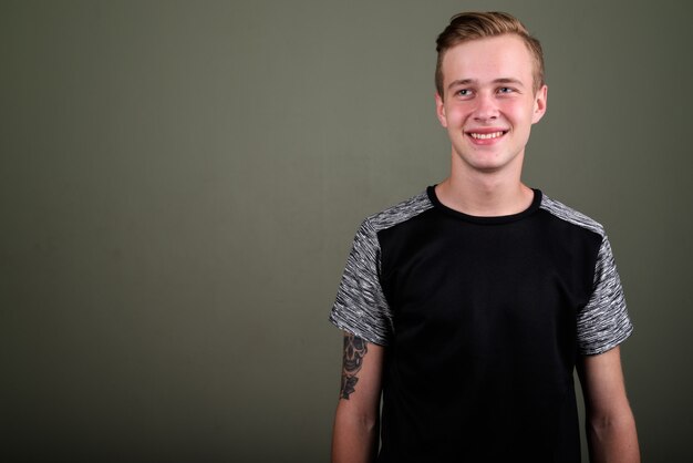 Foto de estudio de joven guapo con cabello rubio contra el fondo de color