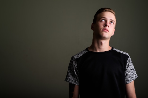 Foto de estudio de joven guapo con cabello rubio contra el fondo de color