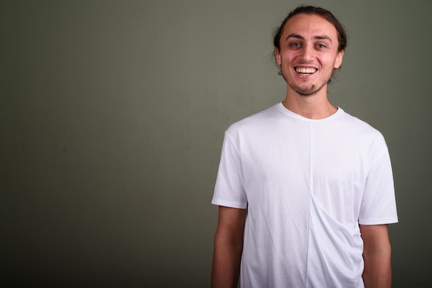 Foto de estudio de joven guapo con camisa blanca contra el fondo de color