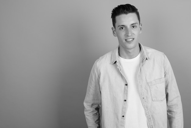 Foto de estudio de joven guapo contra un fondo gris en blanco y negro