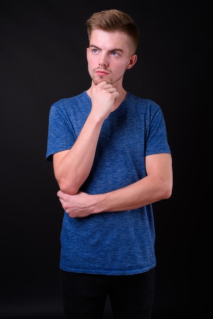 Foto de estudio de joven guapo contra fondo negro