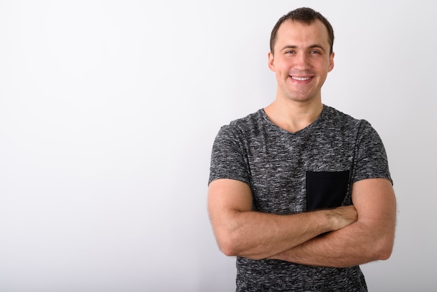 Foto de estudio de joven musculoso feliz sonriendo con brazos cruzados