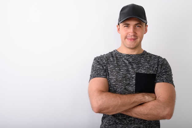 Foto foto de estudio de joven musculoso con gorra con los brazos cruzados