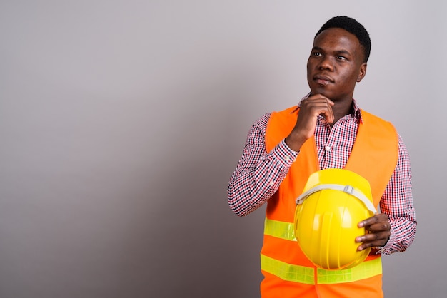 Foto de estudio de joven trabajador de la construcción africana contra el fondo blanco.