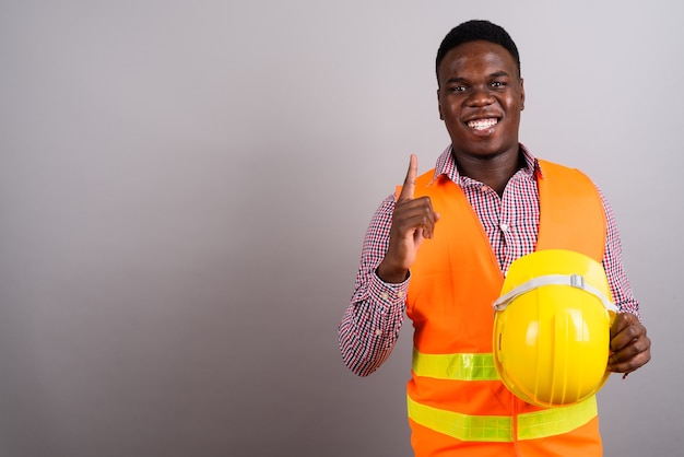 Foto de estudio de joven trabajador de la construcción africana contra el fondo blanco.