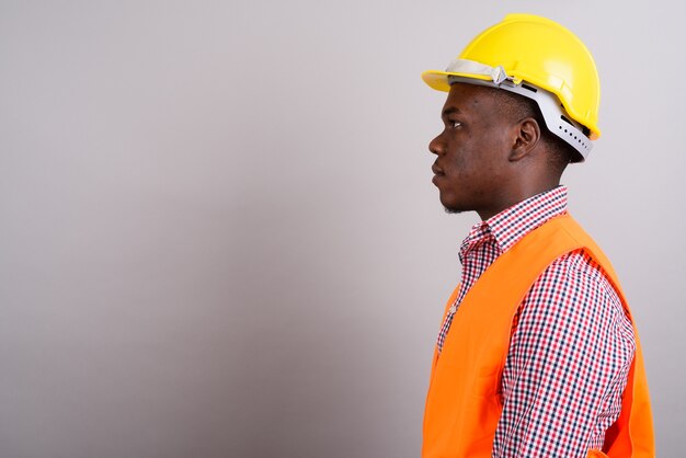 Foto de estudio de joven trabajador de la construcción africana contra el fondo blanco.