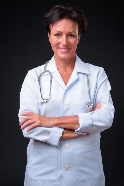 Foto de estudio de madura hermosa doctora escandinava con pelo corto sobre fondo negro