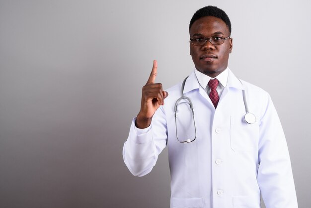 Foto de estudio de médico joven africano con anteojos contra el fondo blanco.