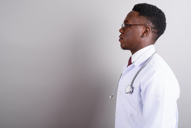 Foto de estudio de médico joven africano con anteojos contra el fondo blanco.