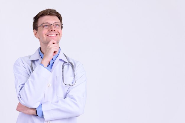 Foto de estudio de médico joven apuesto con anteojos contra un blanco