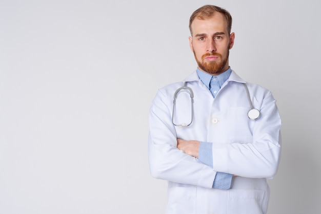 Foto de estudio de médico joven barbudo contra un blanco