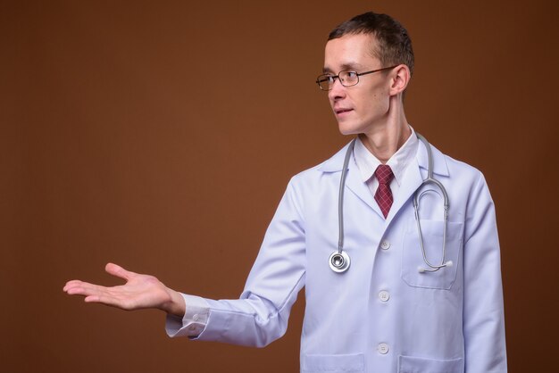 Foto de estudio de médico joven en marrón