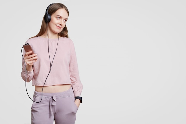 Foto de estudio de mujer atractiva complacida vestida con ropa casual