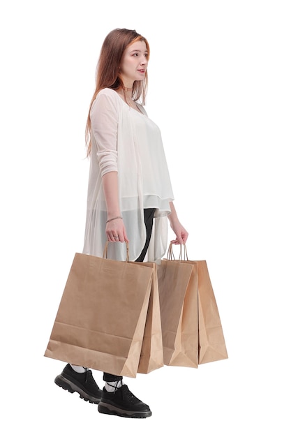 Foto de estudio de una mujer bonita caminando, llevando bolsas de papel. Fondo blanco.