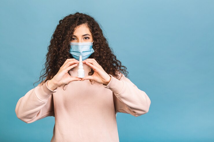 Foto foto de estudio de mujer infectada con spray nasal en las manos, dama con mascarilla protectora