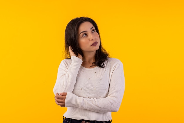 Foto de estudio de mujer joven con camisa blanca sobre fondo amarillo con diversas expresiones faciales