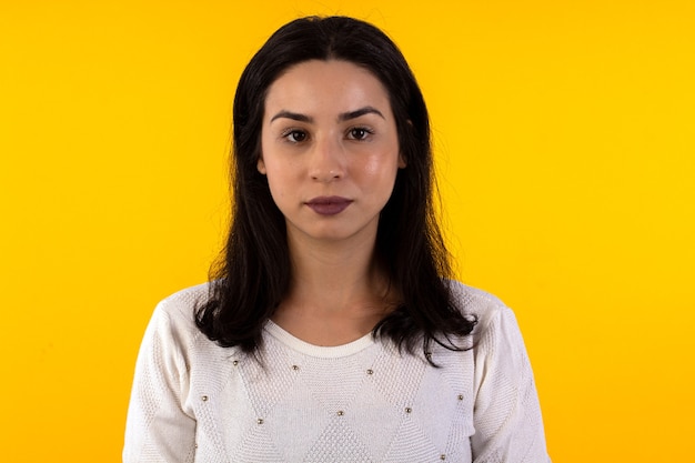 Foto de estudio de mujer joven con camisa blanca sobre fondo amarillo con diversas expresiones faciales