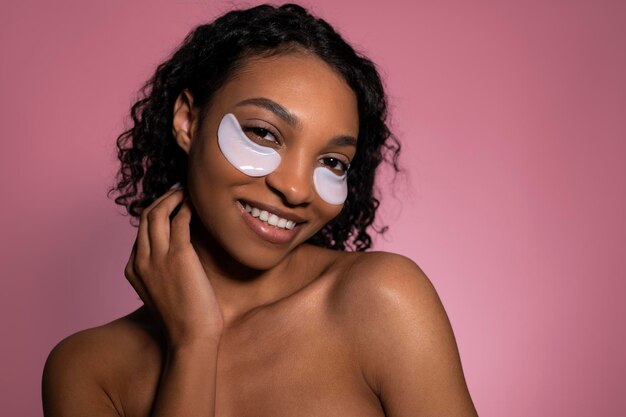 Foto foto de estudio en primer plano de una niña de piel oscura feliz y sonriente con parches debajo de los ojos concepto de belleza