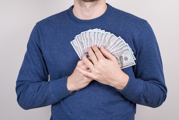 Foto de estudio de primer plano recortada de chico enamorarse de dinero con fondo gris aislado de pecho de corazón