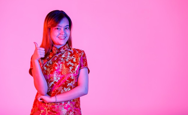 Foto de estudio de retrato de modelo femenino de cabello teñido adolescente asiático milenario vistiendo hermoso oro y rojo chino tradicional cheongsam qipao camisa de pie sonriendo mirar a cámara sobre fondo blanco.