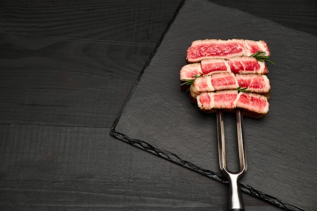 Foto de estudio de rodajas de bistec en un tenedor de carne