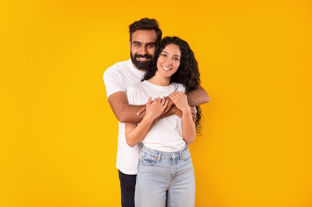 Foto foto de estudio de una romántica pareja árabe abrazándose sobre fondo amarillo