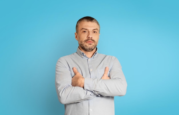 Foto de estudio de serio varón de mediana edad sobre fondo azul.