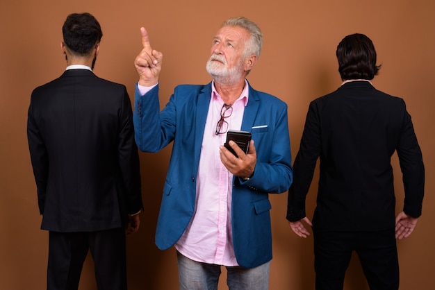 Foto de estudio de tres empresarios barbudos multiétnicos juntos contra el fondo marrón