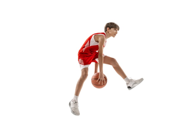 Foto de estudio de vista lateral completa de un joven jugador de baloncesto con uniforme rojo entrenando aislado sobre fondo blanco