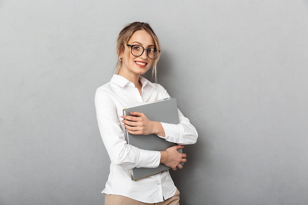 Foto de exitosa empresaria con gafas sosteniendo carpetas de papel en la oficina, aislado