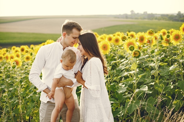 Foto de una familia joven en el campo de girasoles en un día soleado.