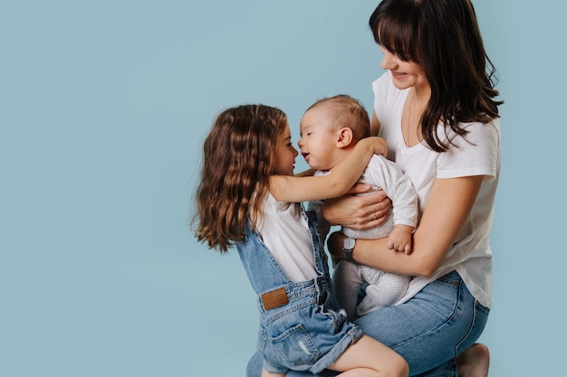 Foto foto de familia, niños y mamá abrazándose juntos, sentados en el piso del estudio