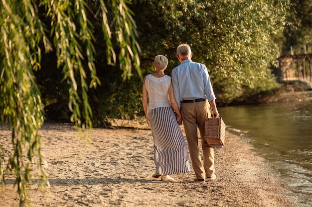 Una foto de una feliz pareja de ancianos yendo de picnic a la orilla del río