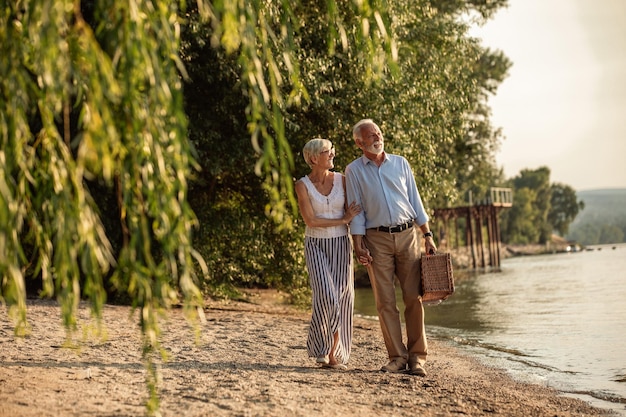 Una foto de una feliz pareja de ancianos yendo de picnic a la orilla del río