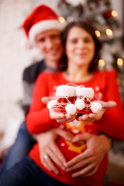 Foto de la feliz pareja casada con botines sobre fondo de adornos navideños