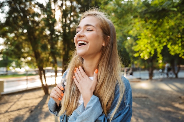 Foto de una feliz risa positiva alegre joven caminando afuera en el parque natural verde.