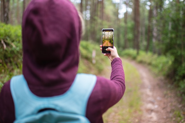 Foto femenina del paisaje forestal con el teléfono inteligente en la mano