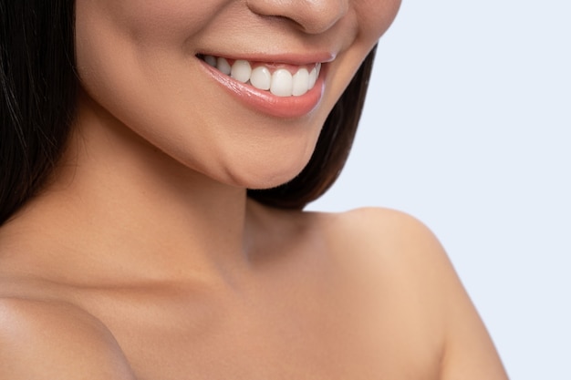 Foto focada. Menina morena alegre sorrindo, isolada em um fundo branco