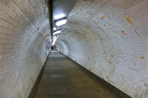 Foto de gran angular del túnel de pie de Greenwich bajo el río Támesis, la gente se aleja a lo lejos.