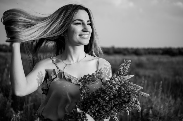 Foto gris mujer en camisa de pie en el campo con el ramo de flores