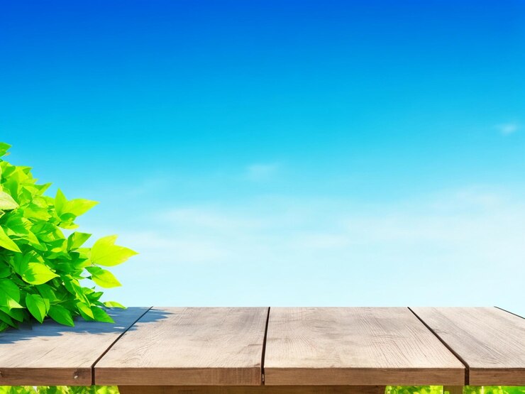 Foto grüne Blätter und ein Holztisch mit verschwommenem blauen Himmelshintergrund